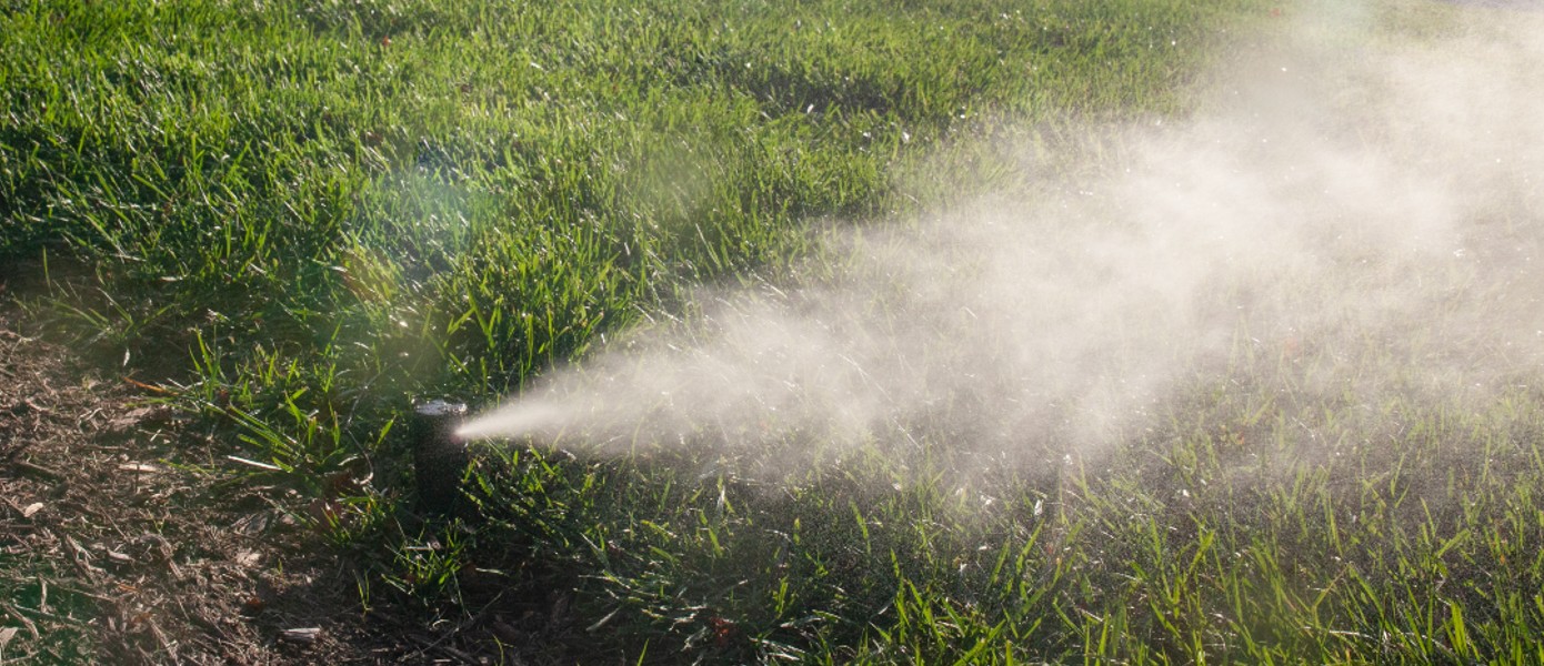 close up of sprinkler spraying grass